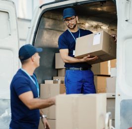 young-worker-loading-cardboard-boxes-delivery-van-communicating-with-his-colleague